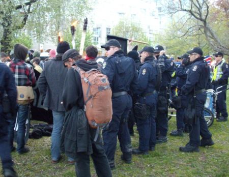As the black bloc shed their outer layer of black clothing behind a banner, a group of PSU cops moved up to observe. As the black bloc shed their outer layer of black clothing behind a banner, a group of PSU cops moved up to observe.